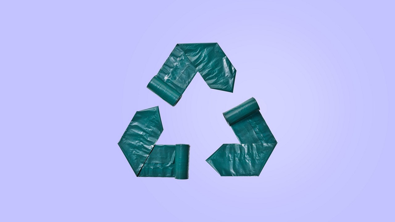 3 Banderolen aus dunkelgrünen Müllbeuteln bilden ein Recycling-Symbol