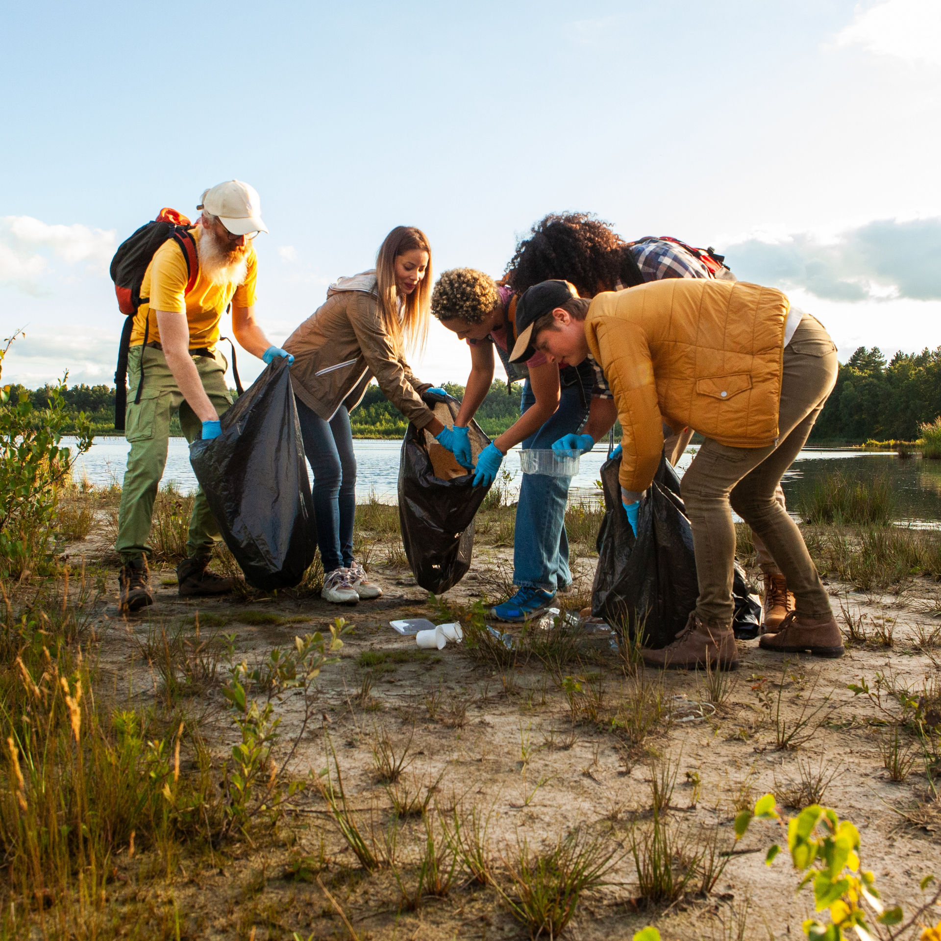 Gruppe von fünf Menschen sammelt gemeinsam Müll in einer Landschaft