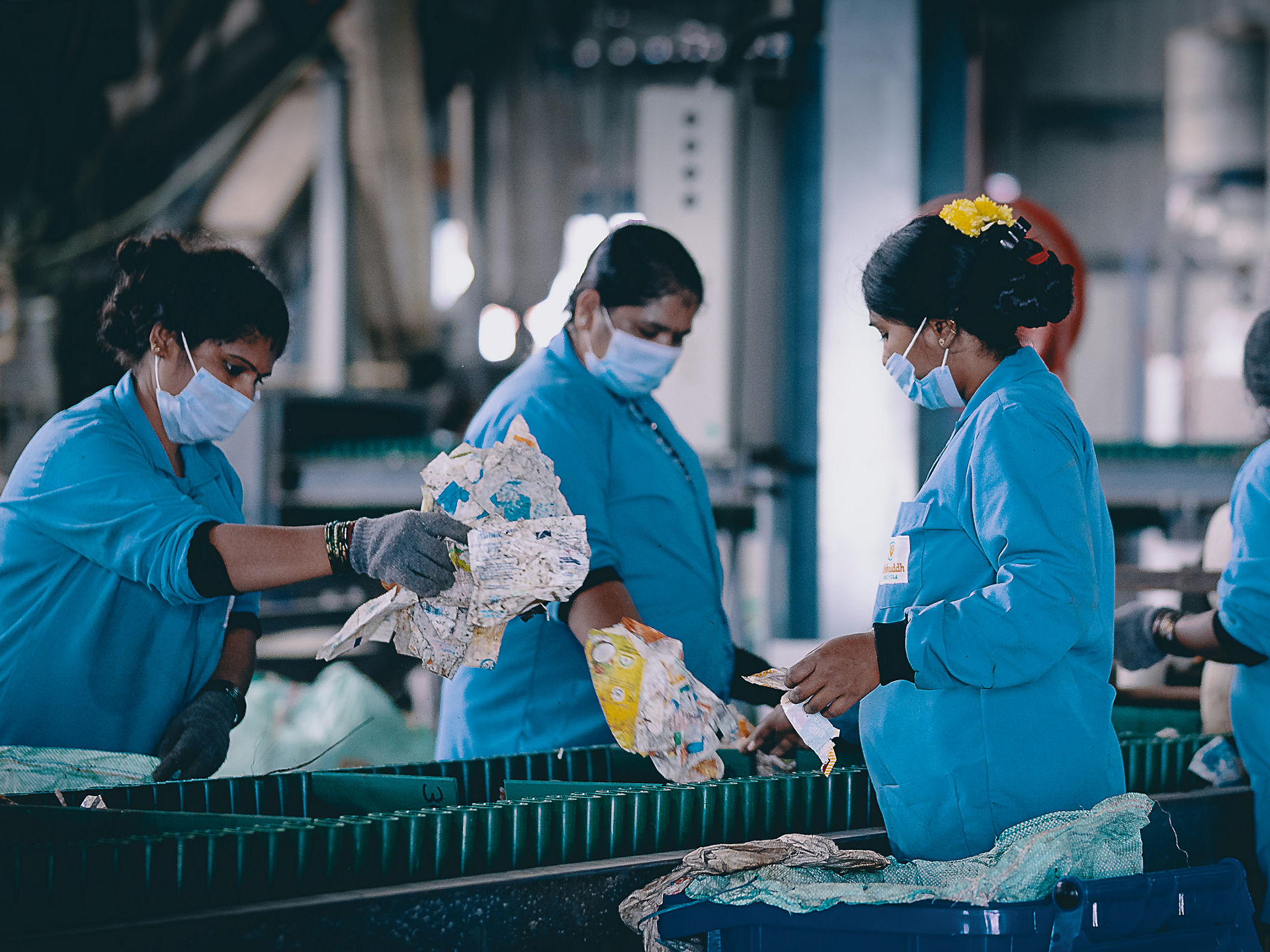Vier Frauen sortieren altes Plastik an Fließband