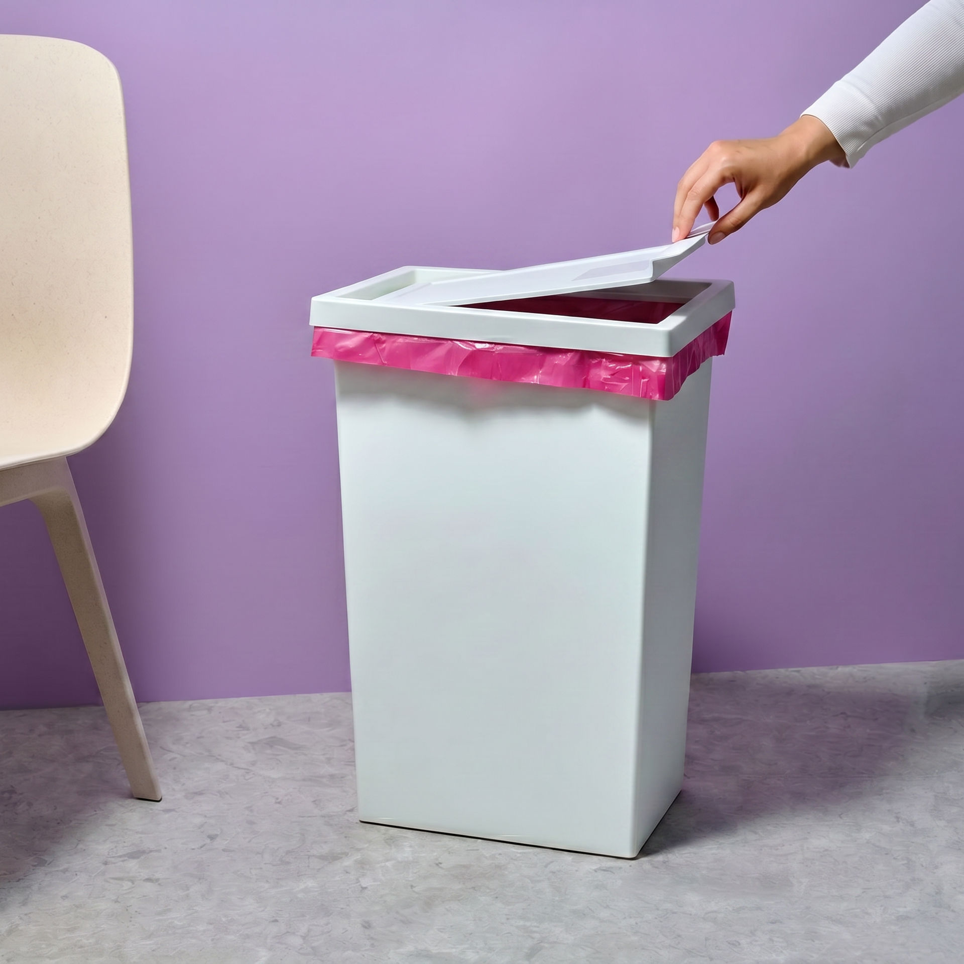 Weißer Mülleimer mit pinkem Müllbeutel neben einem Stuhl vor lila Hintergrund