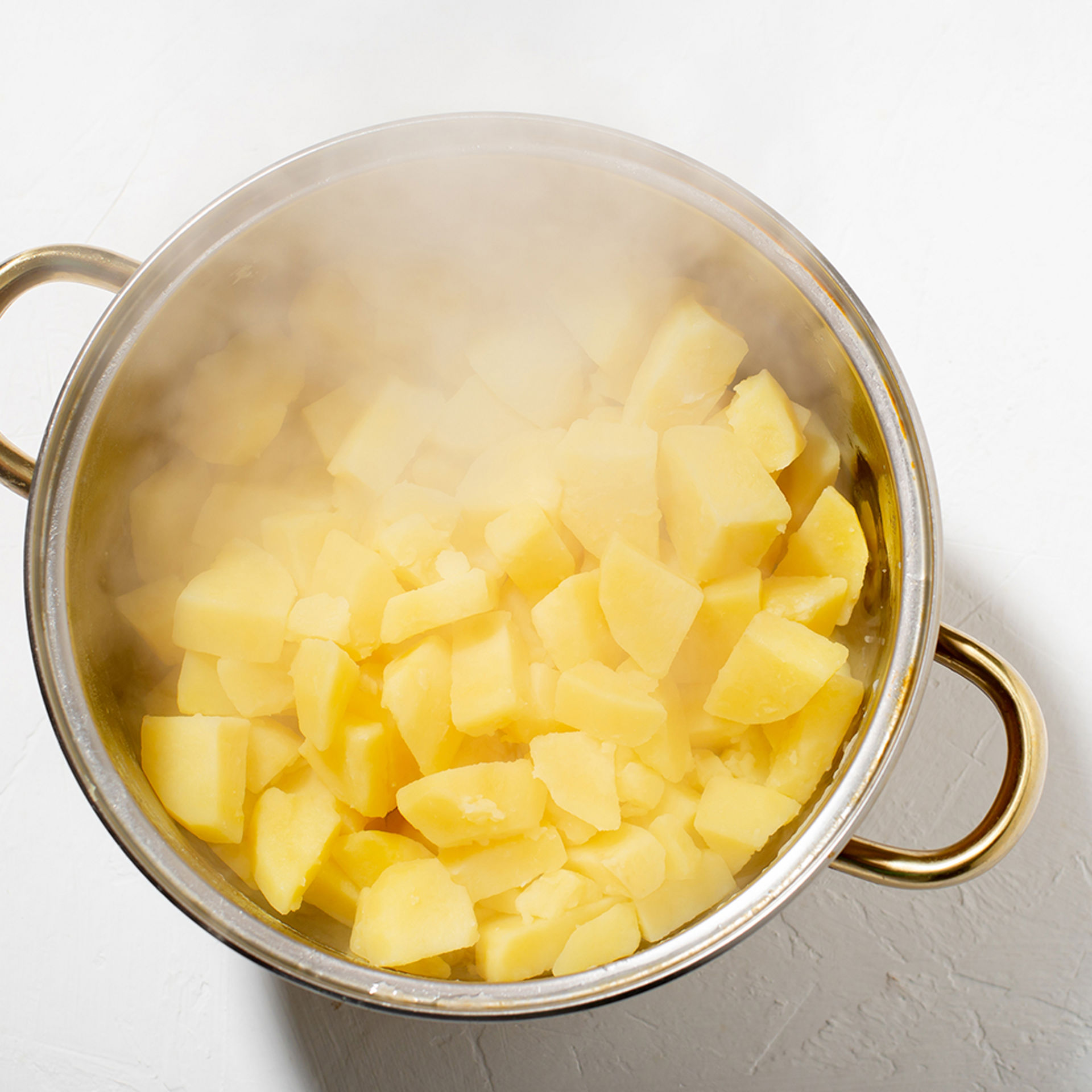 Aus einem Kochtopf mit Kartoffeln steigt Dampf auf