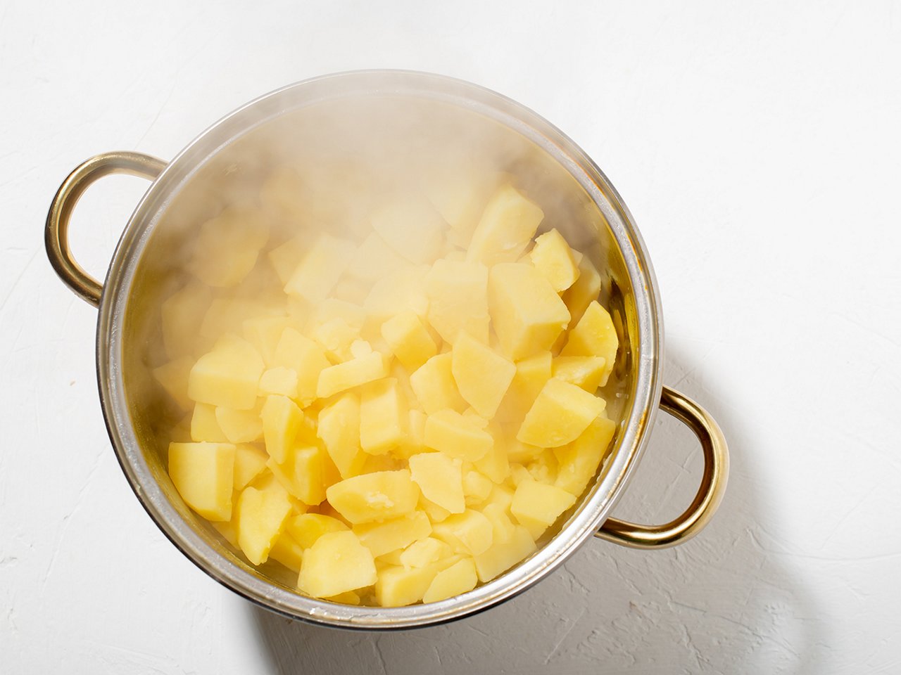 Aus einem Kochtopf mit Kartoffeln steigt Dampf auf