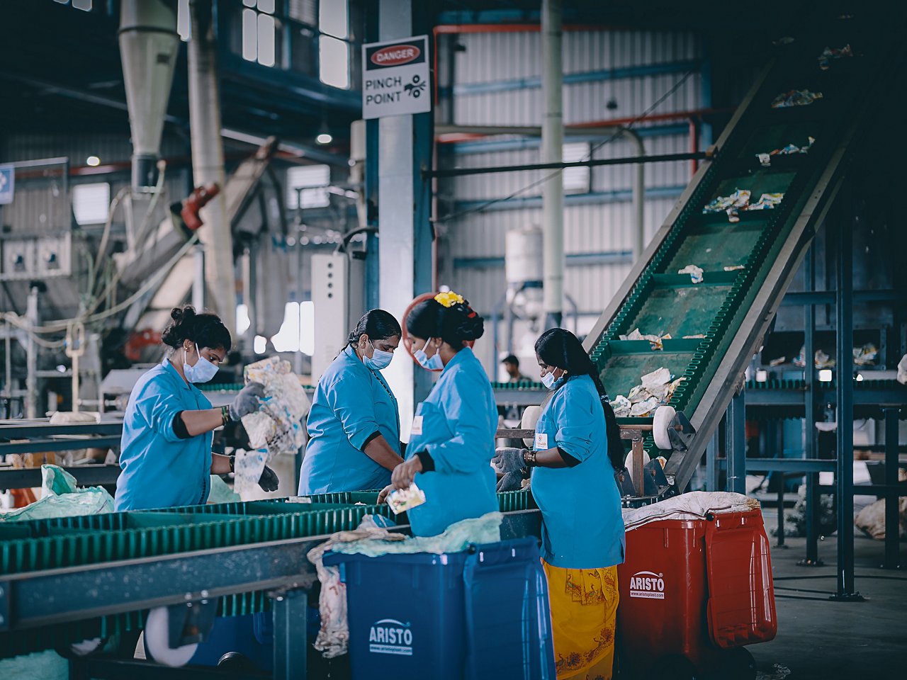 Vier Frauen sortieren altes Plastik an Fließband