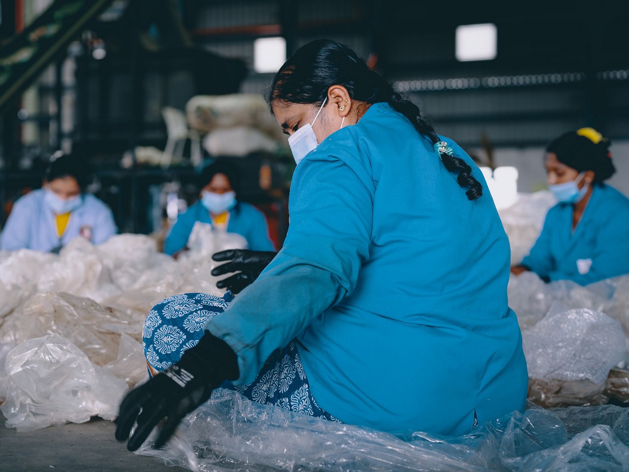 Frauen sortieren auf Boden sitzend altes Plastik in Recycling-Werk