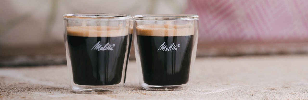 glaeser_2000x650px1.jpg – Melitta® Double-Walled Glasses, accessory product category, shown in a modern kitchen environment with filled coffee beverages