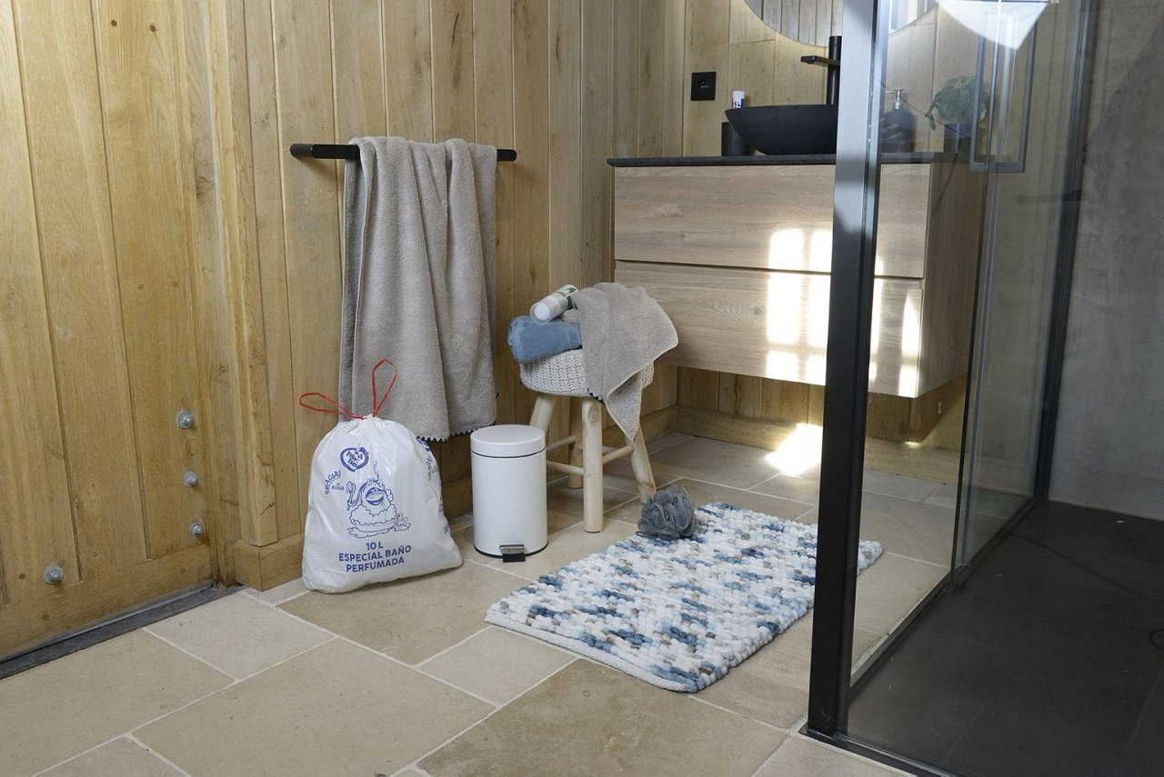 Bolsa de basura Handybag de 10 litros llena colocada en el suelo de un baño