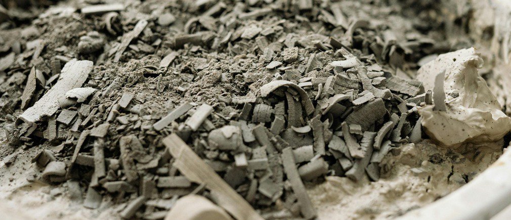 Montón de cenizas grises y trozos de carbón en un recipiente blanco