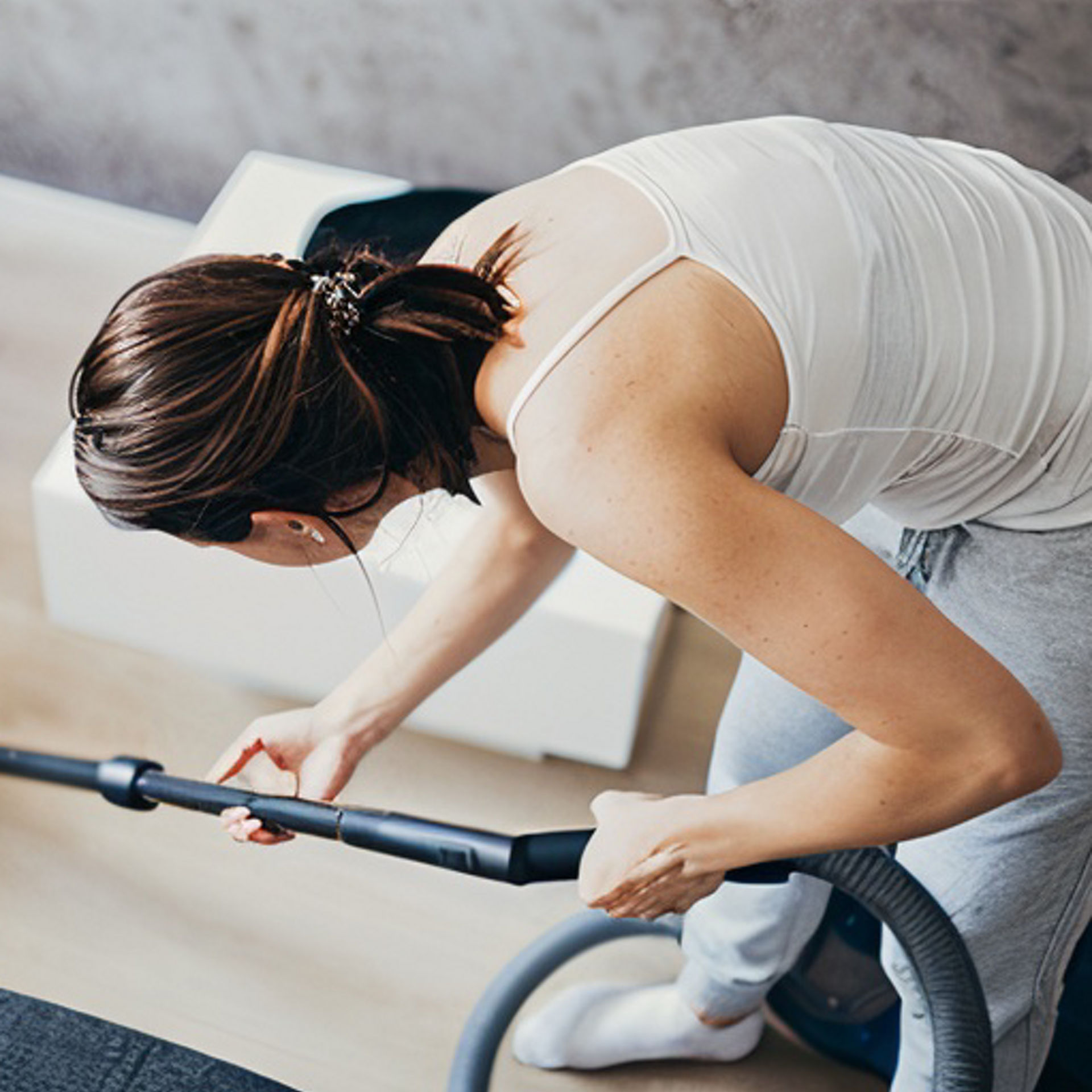 Femme aspirant le sol d’un salon avec un aspirateur