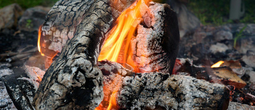 Leños ardiendo con llamas y brasas sobre un lecho de cenizas en una chimenea