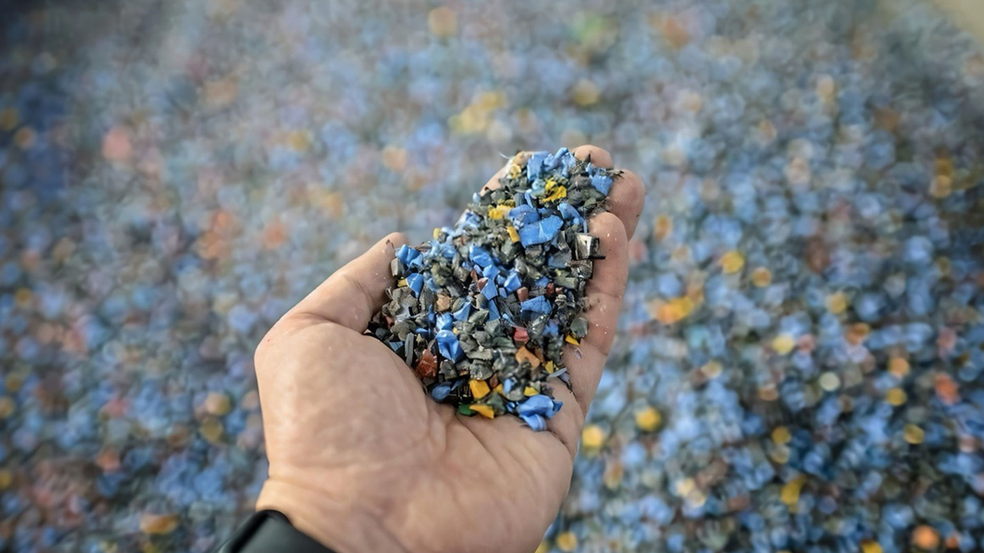 Une main tenant des granules plastiques recyclées sur un fond flou