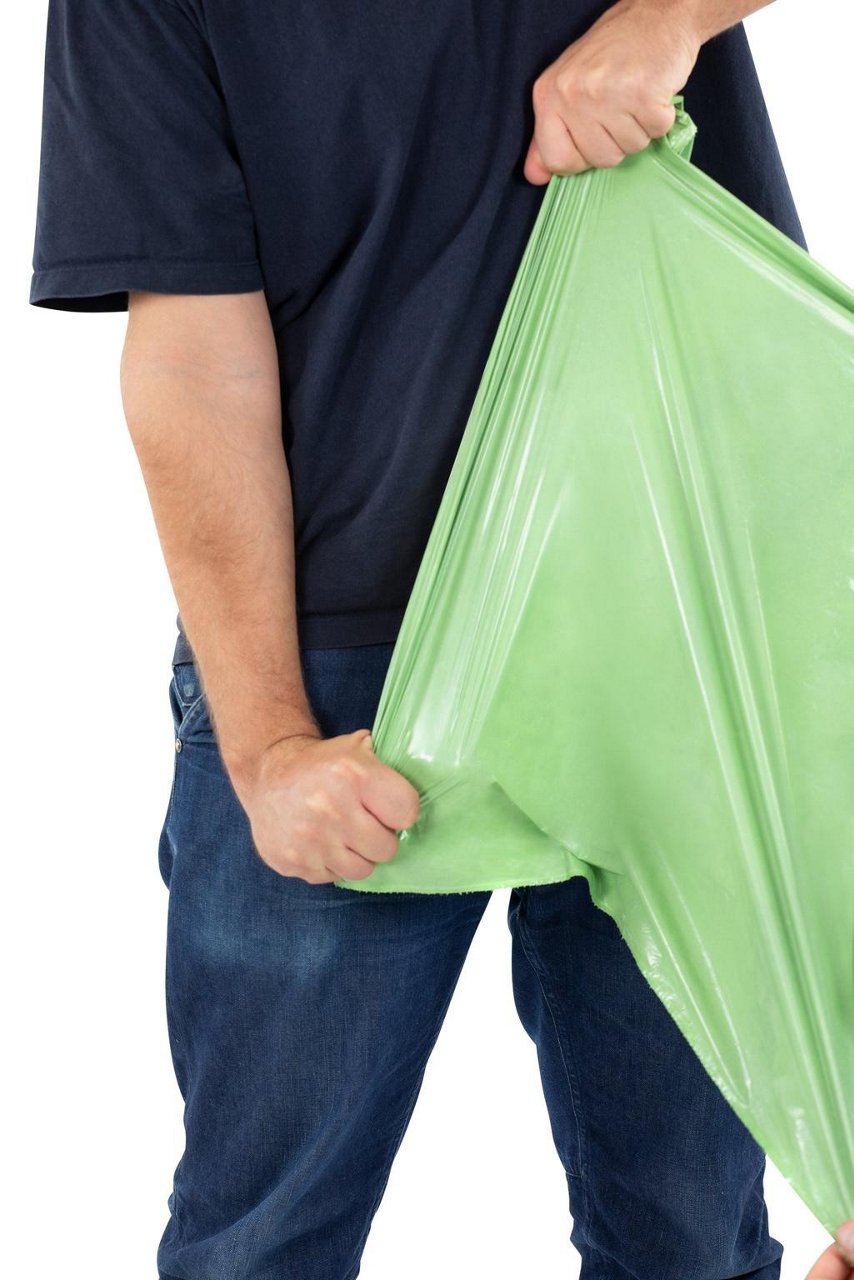 Un homme déchire un sac poubelle Handybag pour démonstration usage