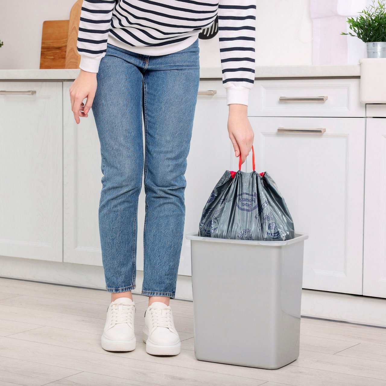 Personne sortant un sac poubelle gris Handy Bag d’un bac dans une cuisine