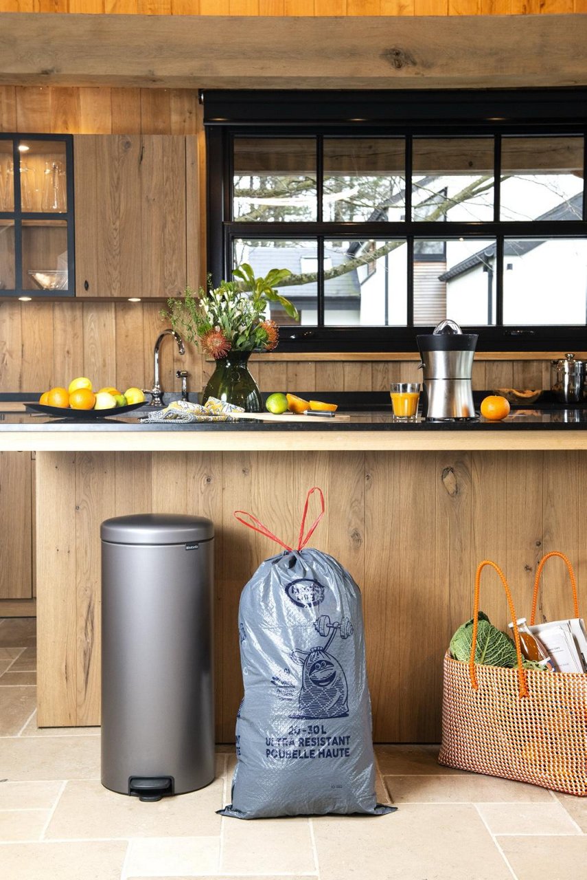 Sac poubelle Handybag avec poignées coulissantes gris devant une poubelle