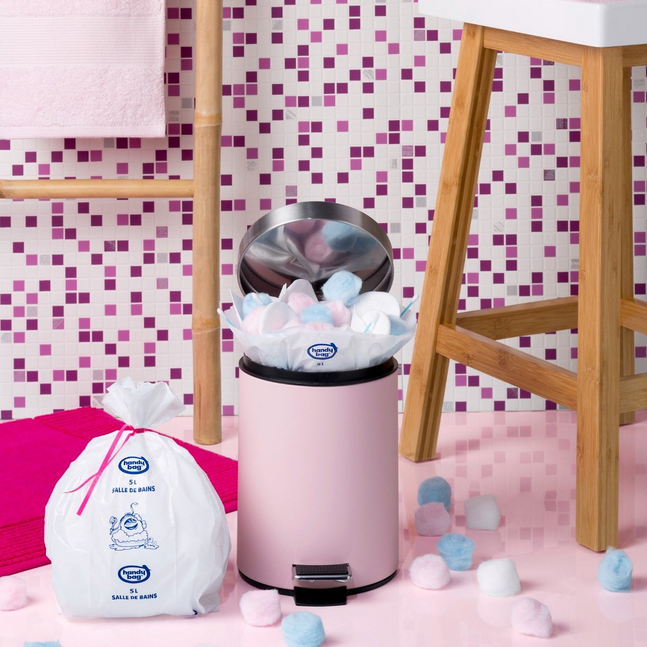Sacs Handy Bag salle de bains près d’une poubelle rose et de serviettes