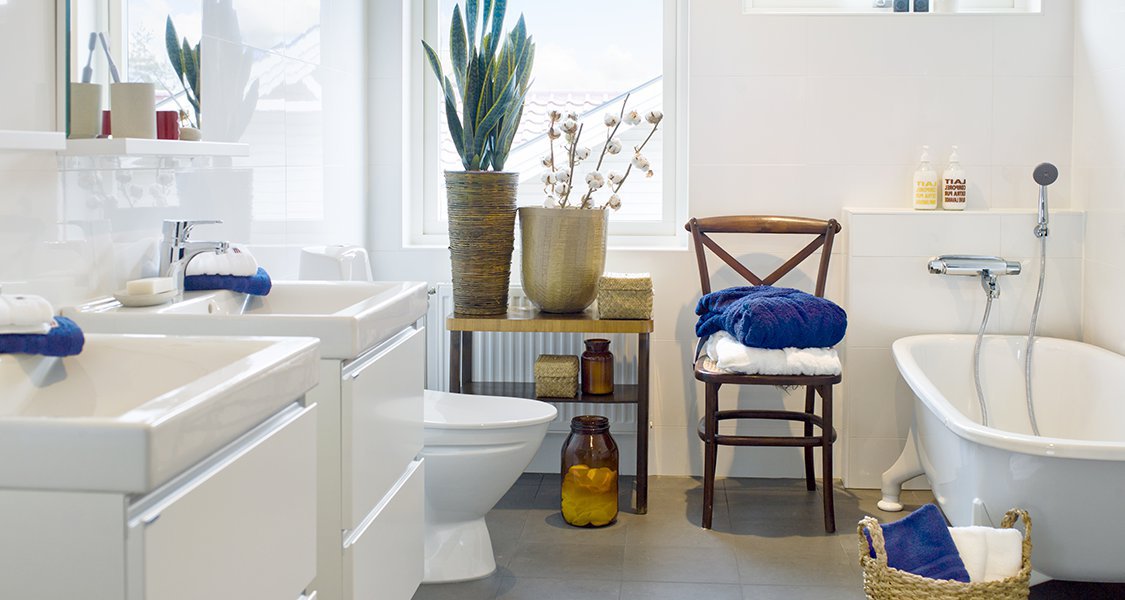 Salle de bain moderne avec double vasque, serviettes pliées sur une chaise et plantes décoratives