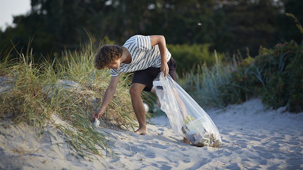 Volontaire nettoyant une plage en ramassant des déchets pour une action écologique responsable