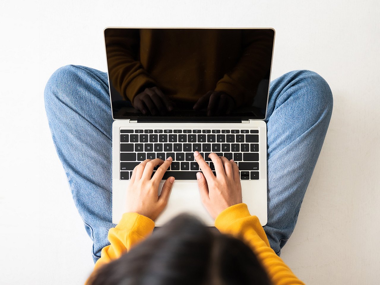 Person tippt auf einem Laptop