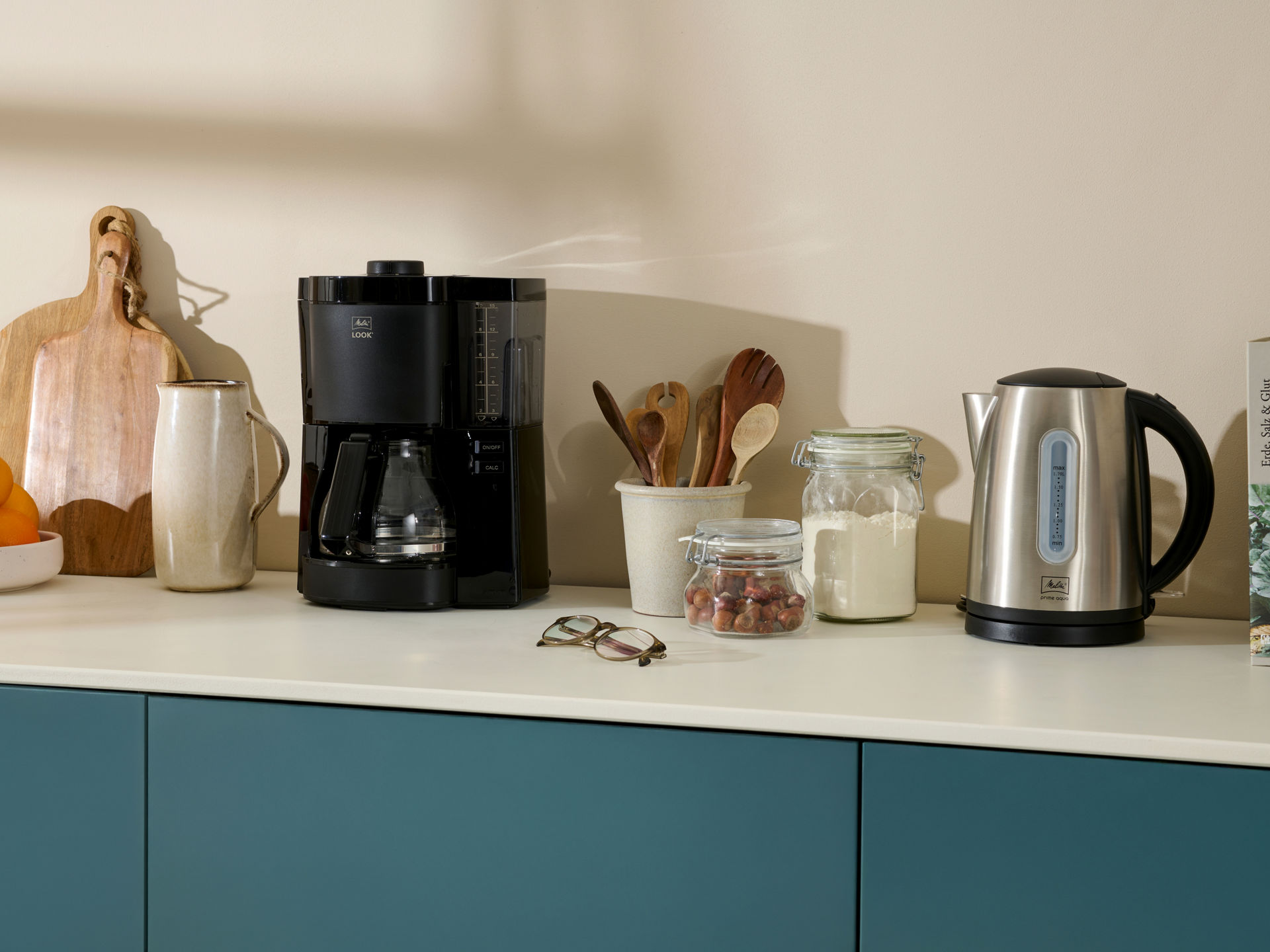 Melitta Filterkaffeemaschine, Melitta Wasserkocher und weitere Küchenutensilien stehen auf einem Küchentresen