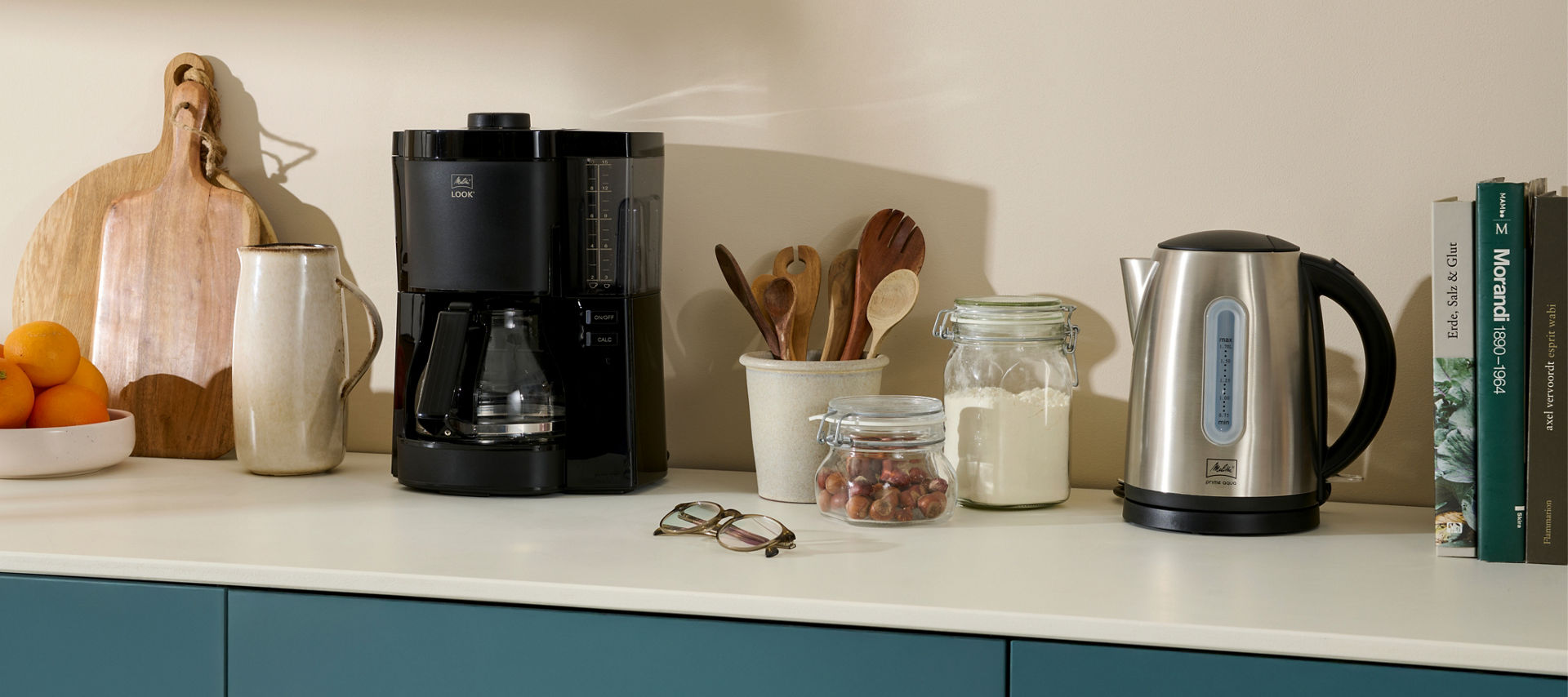 Melitta Filterkaffeemaschine, Melitta Wasserkocher und weitere Küchenutensilien stehen auf einem Küchentresen