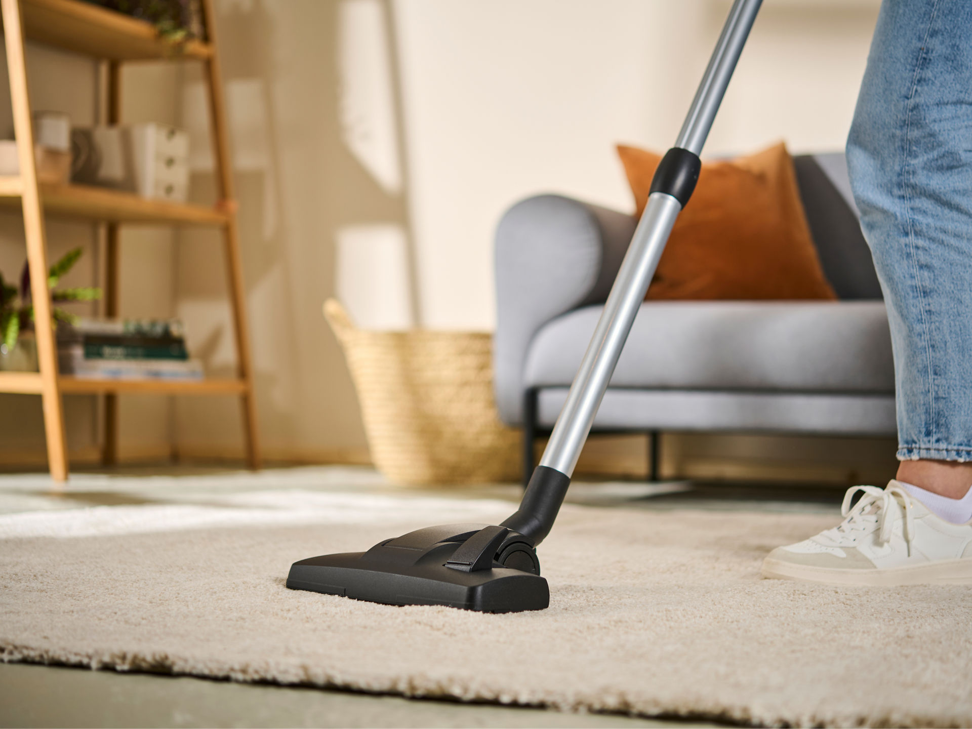 Person saugt einen Teppich im Wohnzimmer mit der Swirl Teppich- und Hartböden Umschaltdüse