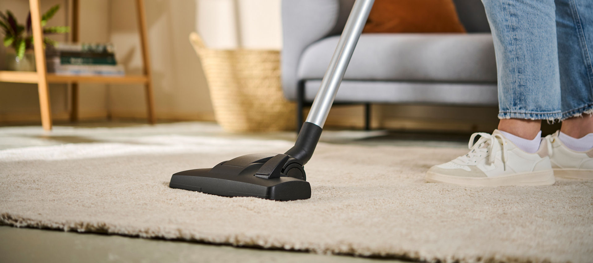 Person saugt einen Teppich im Wohnzimmer mit der Swirl Teppich- und Hartböden Umschaltdüse