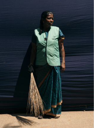 Indische Frau mit Besen vor dunkler Wand