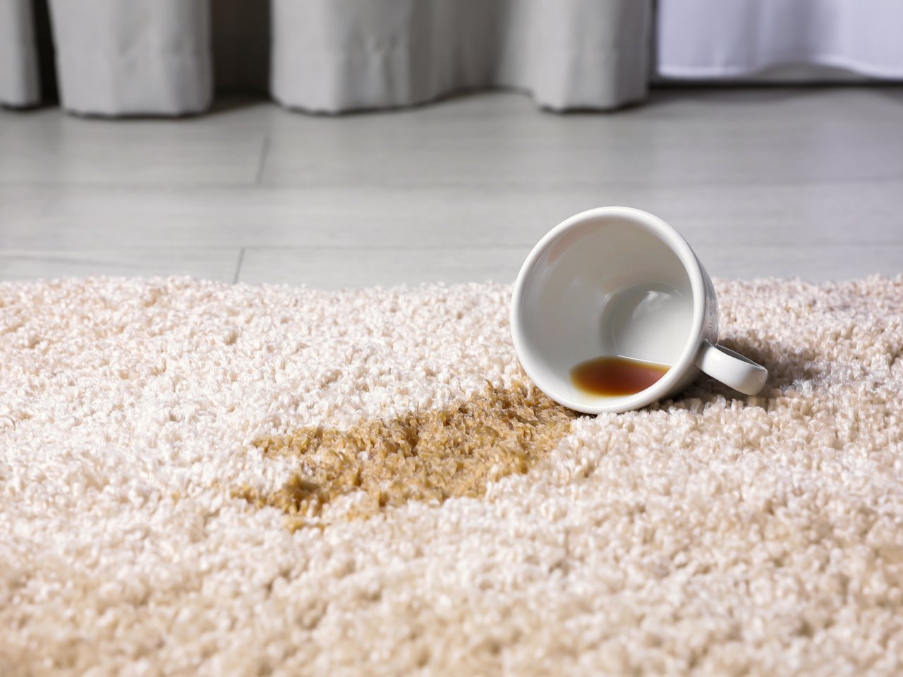 Kaffeefleck auf einem Teppich wegen einer umgestoßenen Tasse