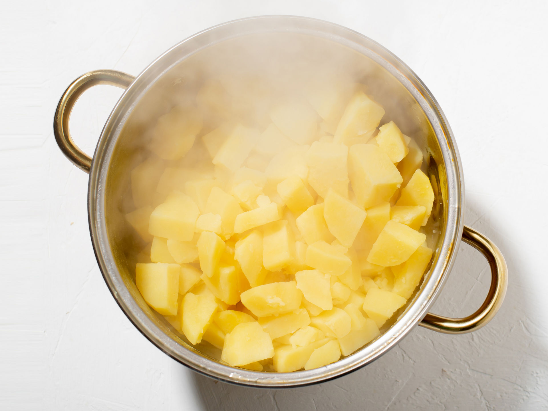 Aus einem Kochtopf mit Kartoffeln steigt Dampf auf