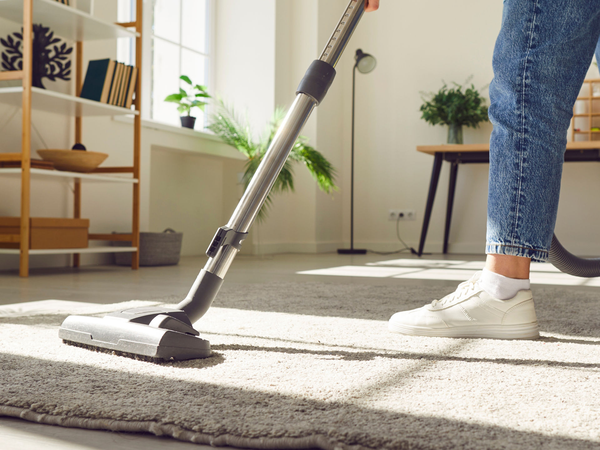 Person saugt Teppich in einem Wohnzimmer