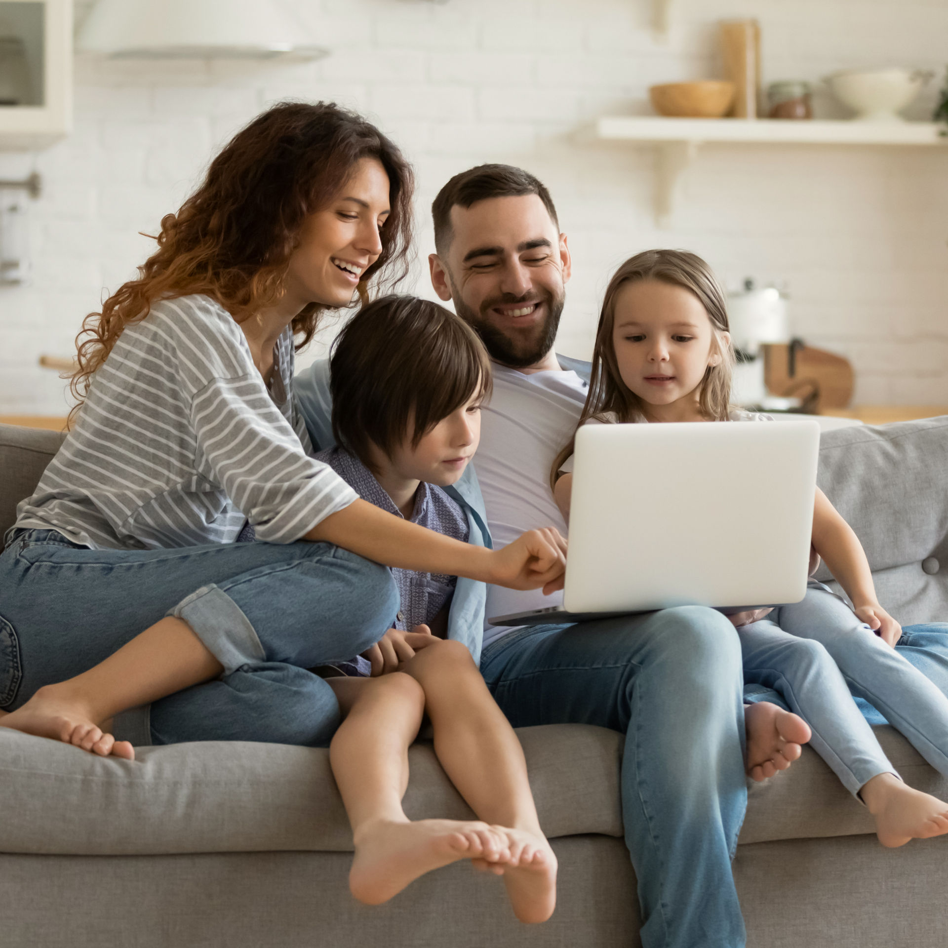 Familie sitzt auf dem Sofa und schaut gemeinsam auf einen Laptop