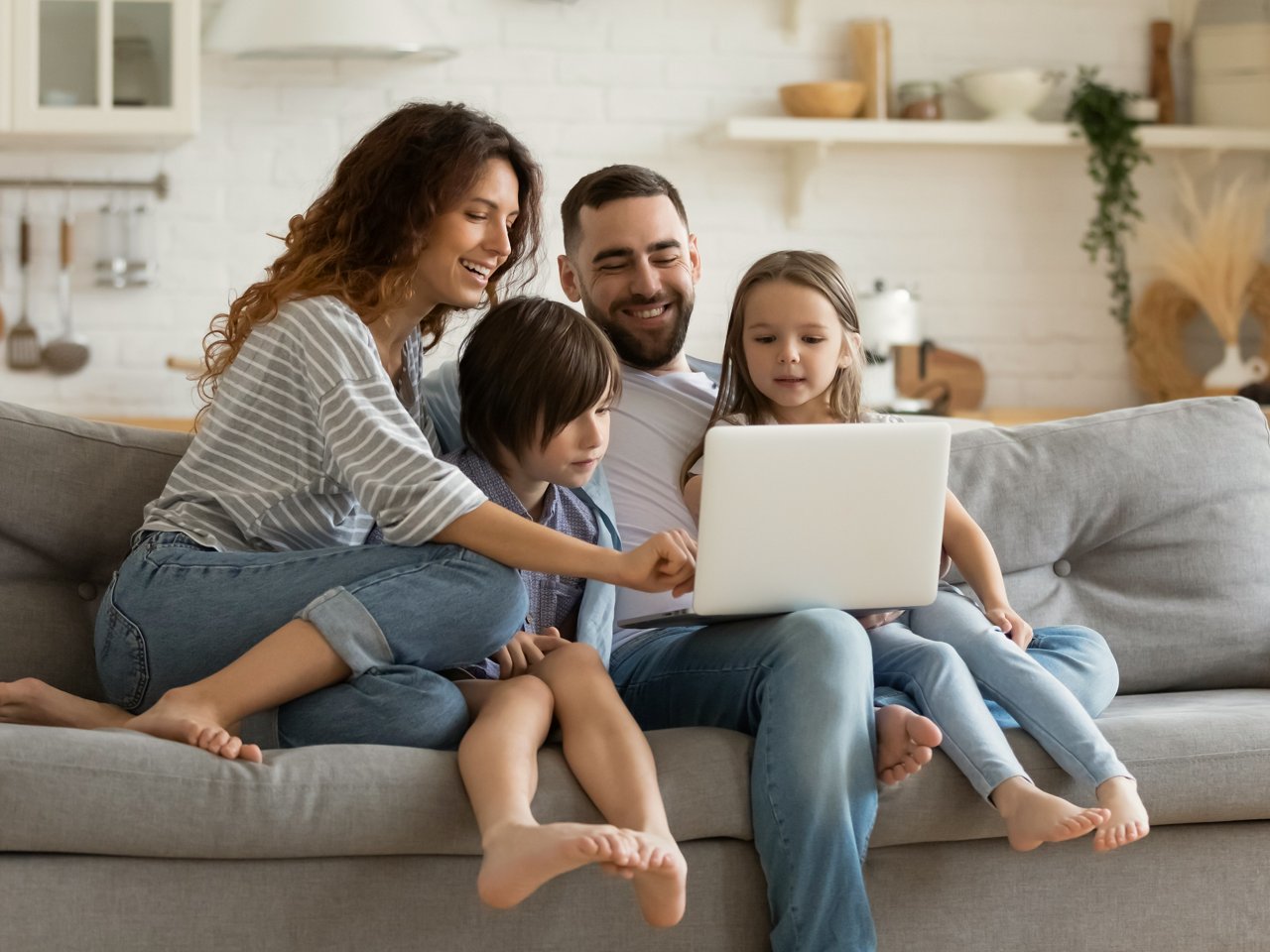 Familie sitzt auf dem Sofa und schaut gemeinsam auf einen Laptop