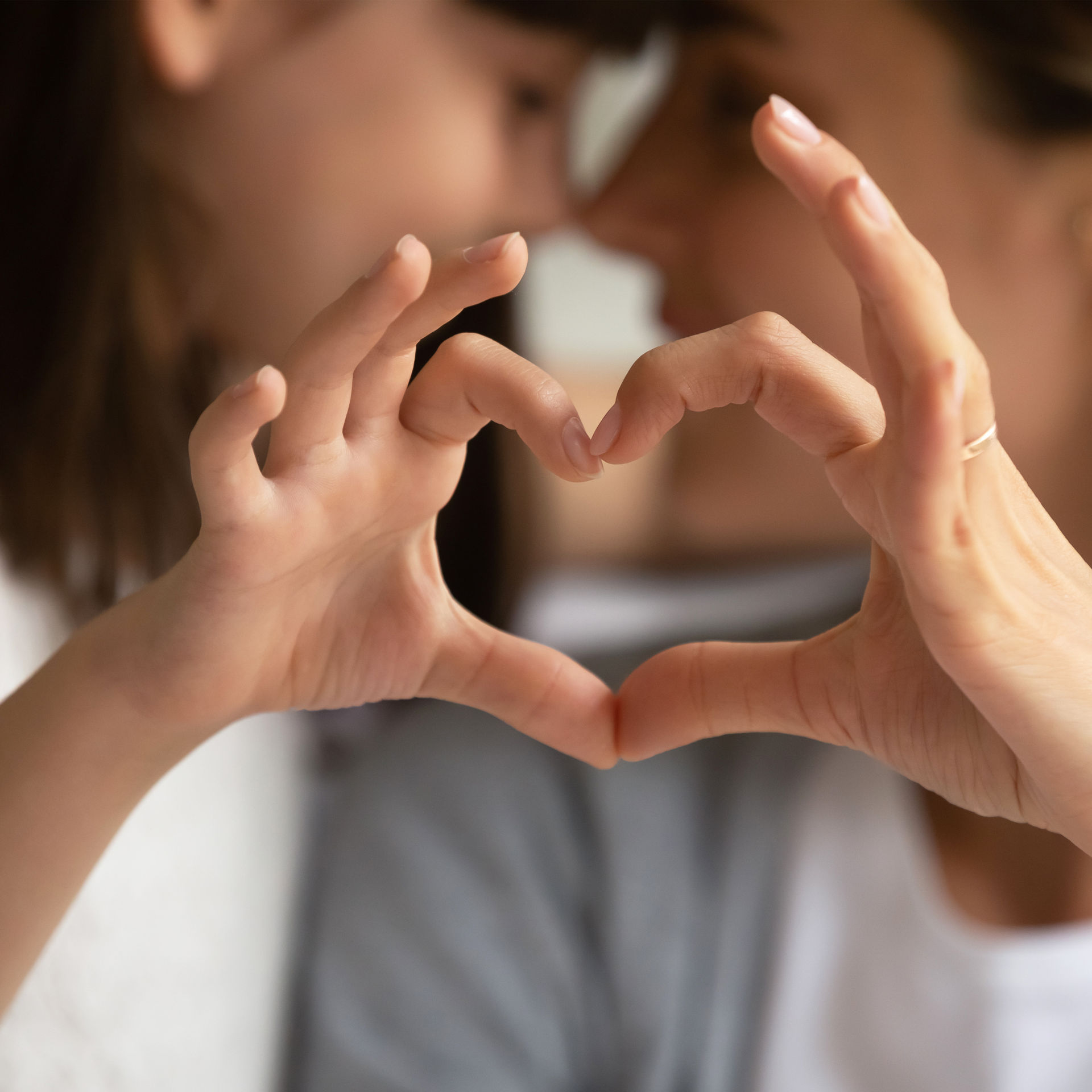 Mutter und Tochter formen ein Herz mit ihren Händen