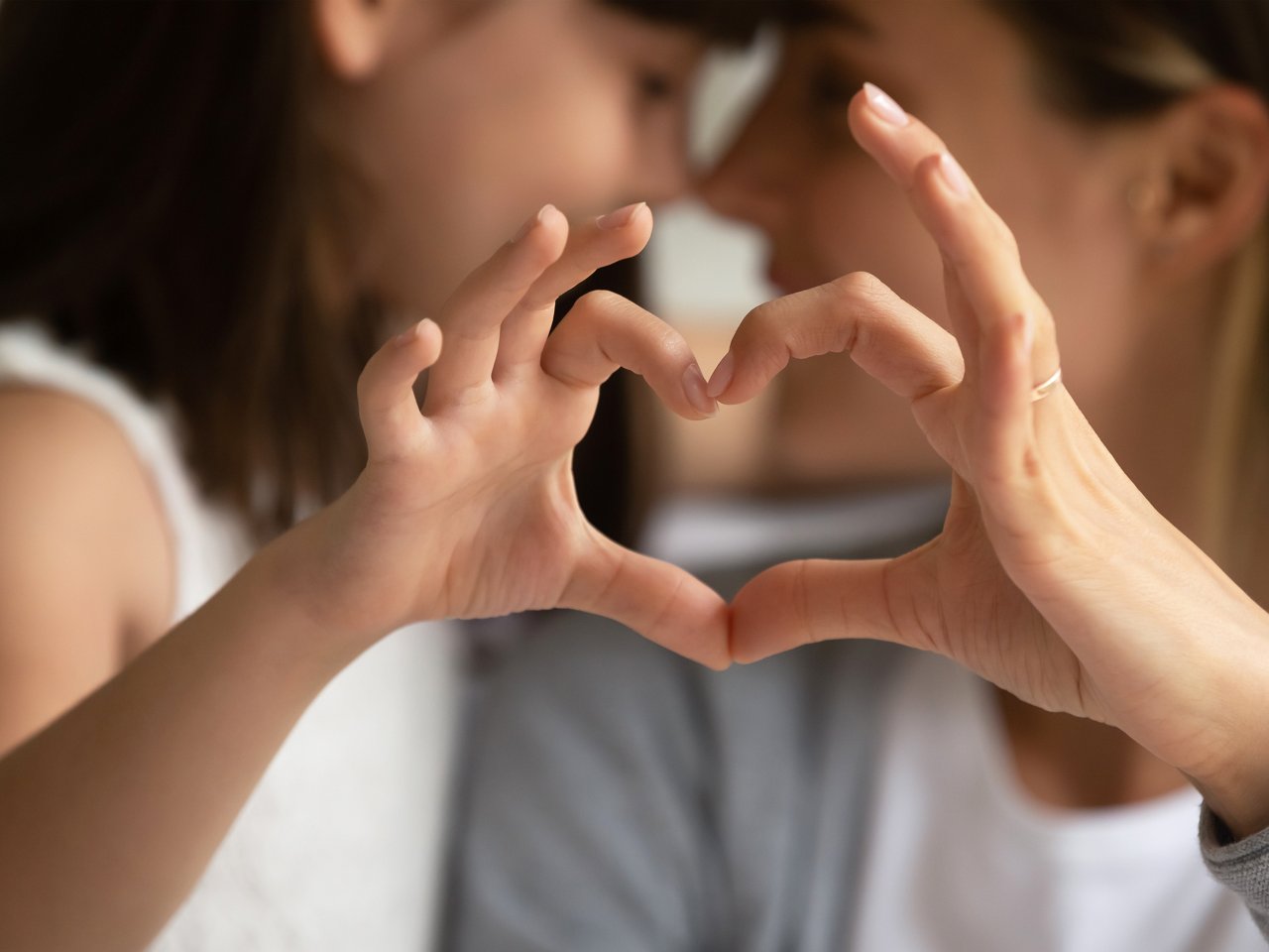 Mutter und Tochter formen ein Herz mit ihren Händen