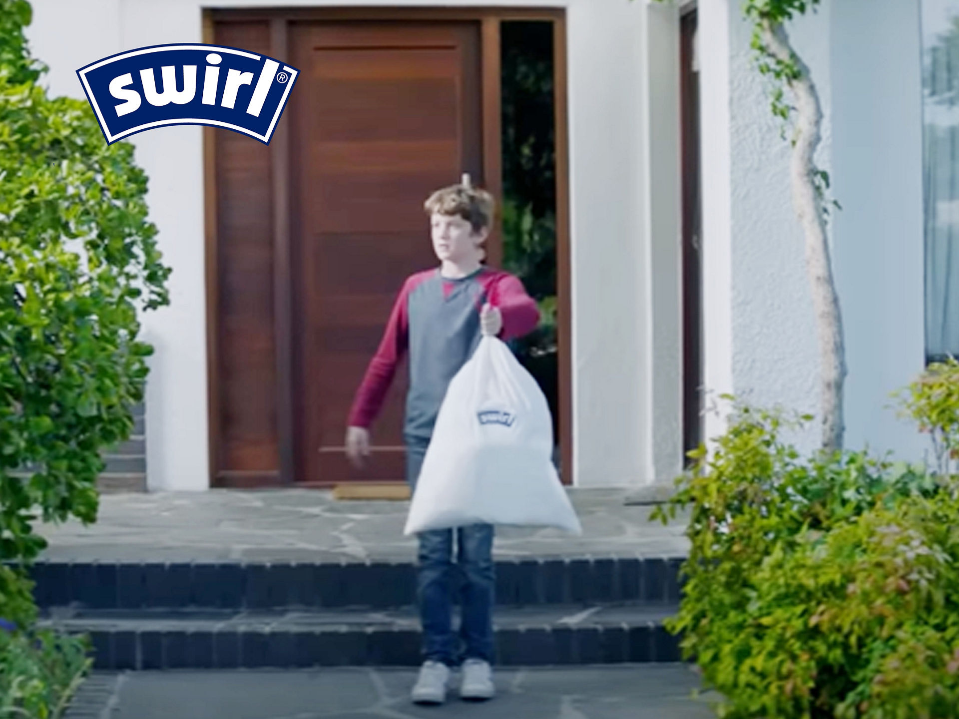 Junge steht draußen vor Haustür mit Swirl Müllbeutel in der Hand