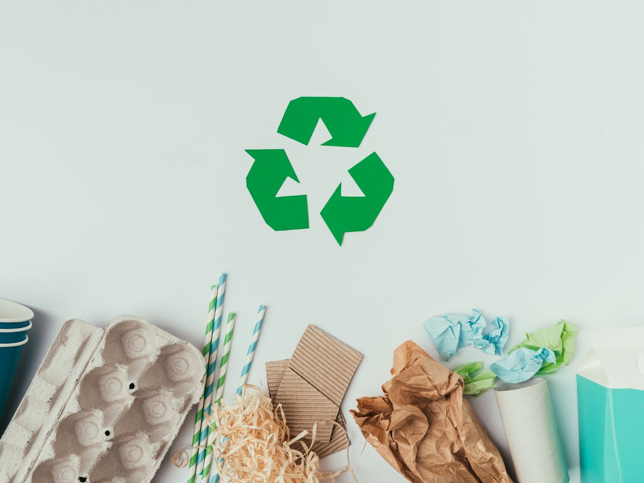 diverse Arten von Müll auf blauem Untergrund und Recyclingsymbol