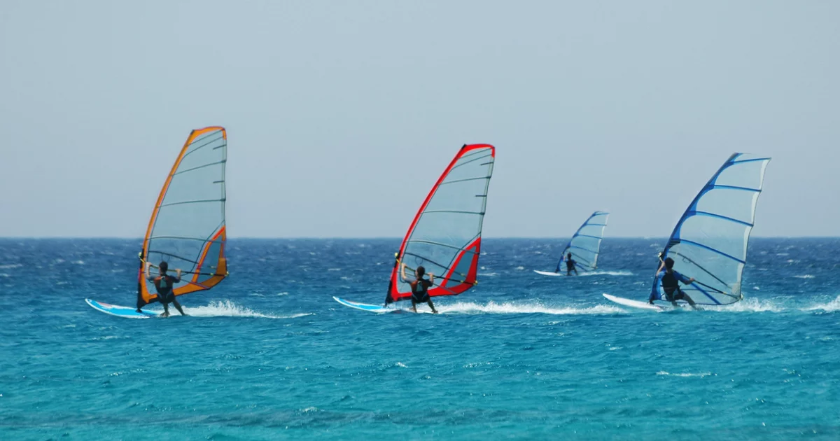 Group of windsurfers gliding across blue sea
