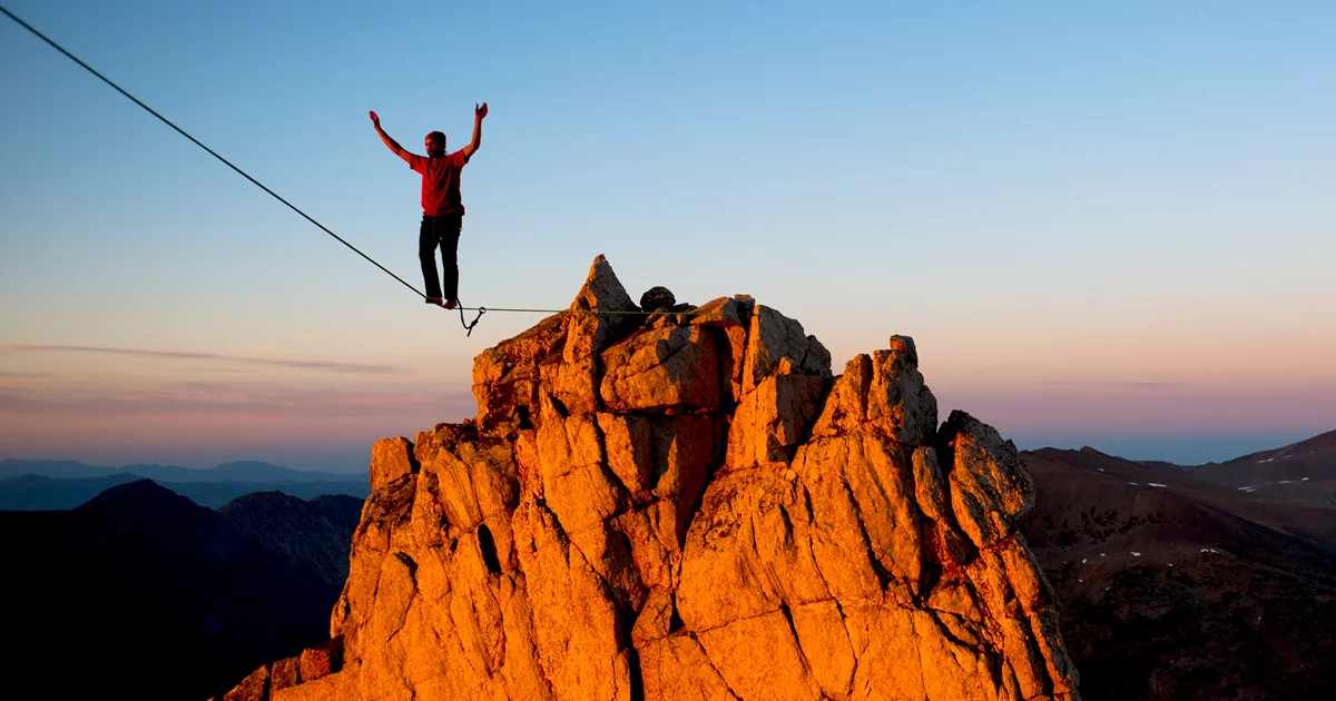 Highliner balancing on rope above mountain peak