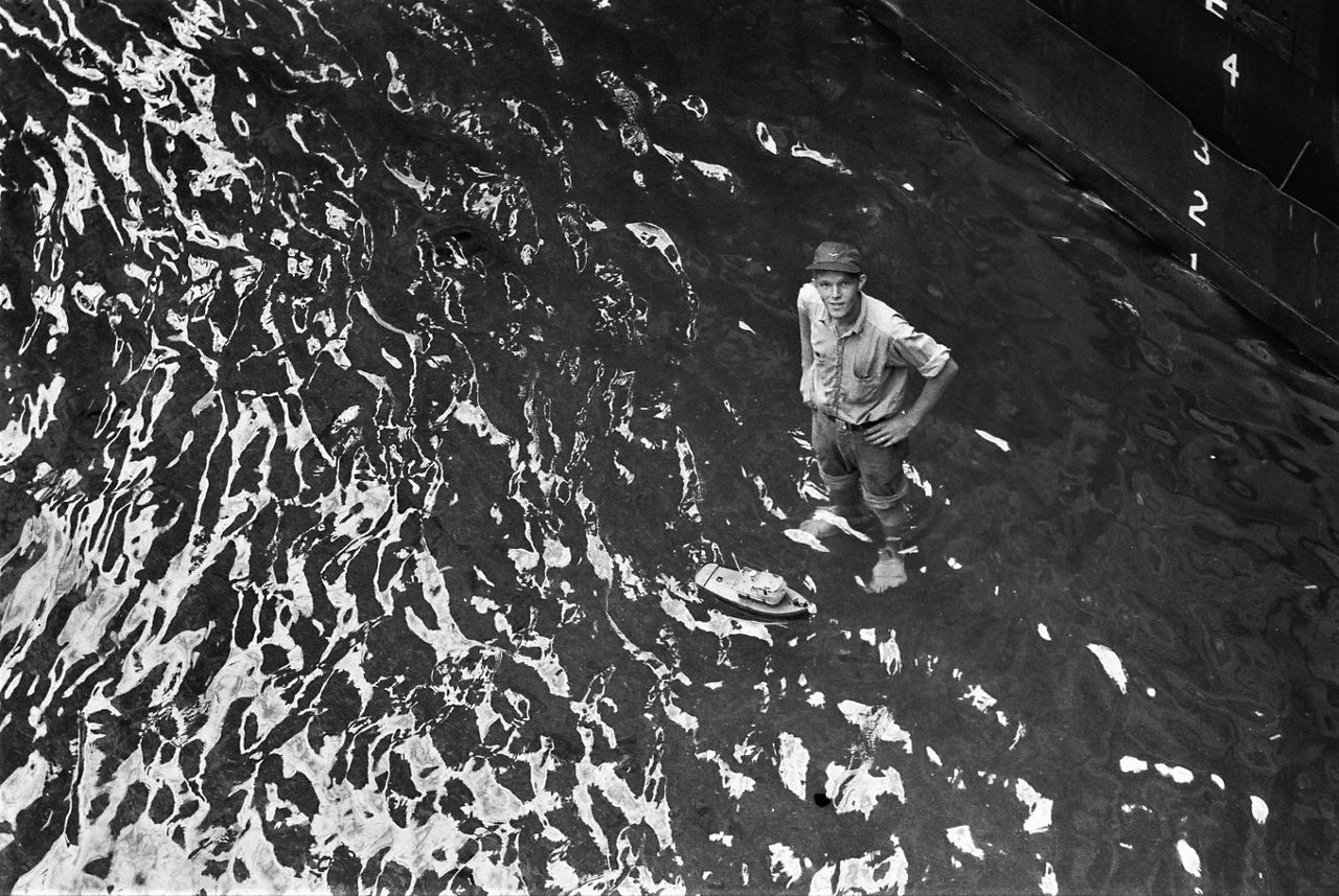 A soldier stands next to a toy boat inside an auxiliary floating dry dock (i.e. a boat that other boats drive into) during a NATO exercise in Türkiye.