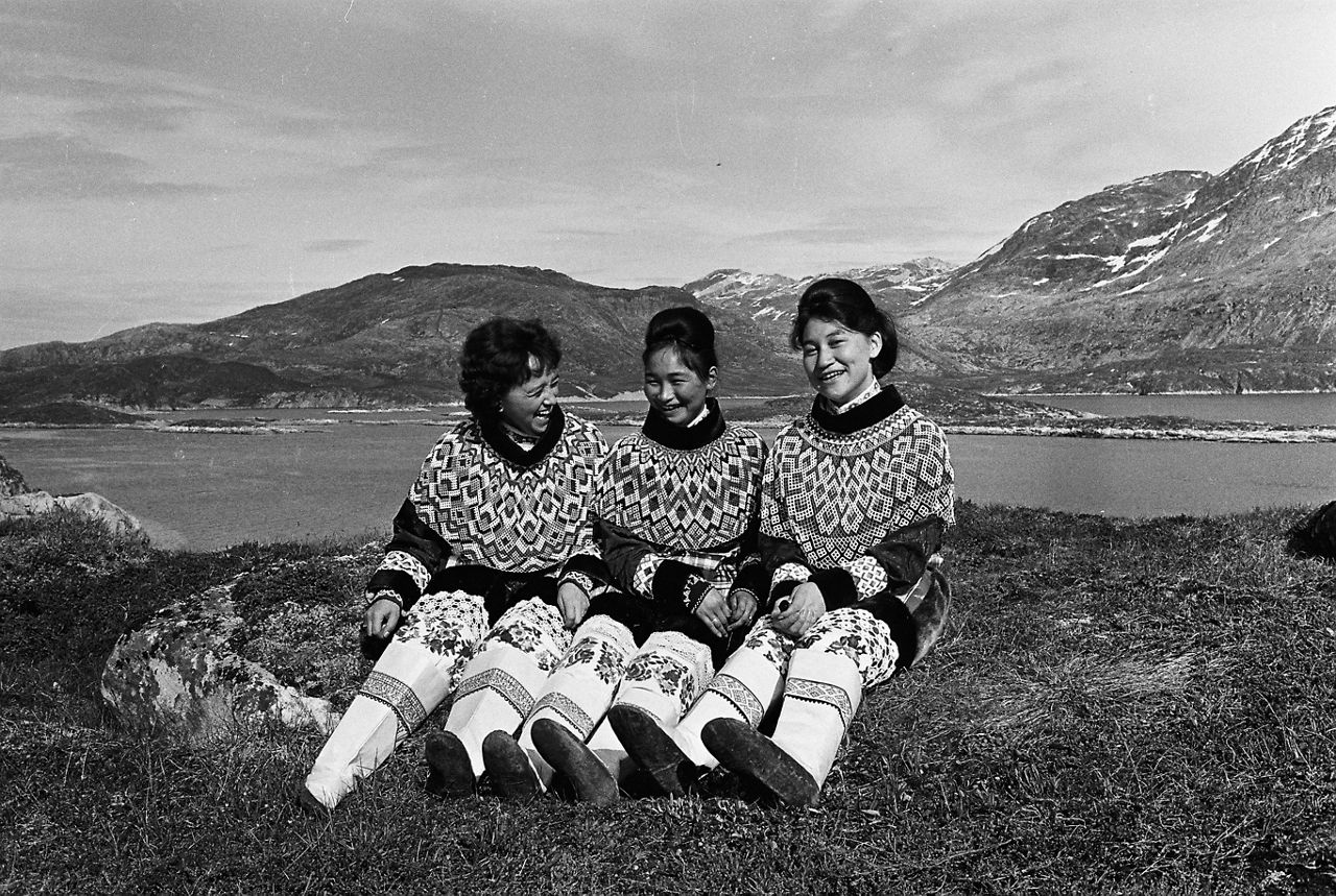 A group of local women share a laugh in front of a stunning natural landscape during a NATO-organised tour for journalists to Greenland in July 1963.