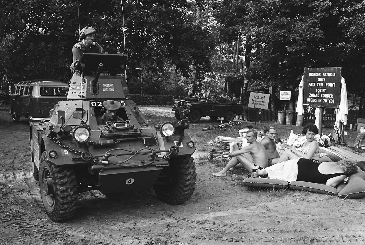 Civilians sunbathe next to an armoured vehicle near the border between East and West Berlin. 