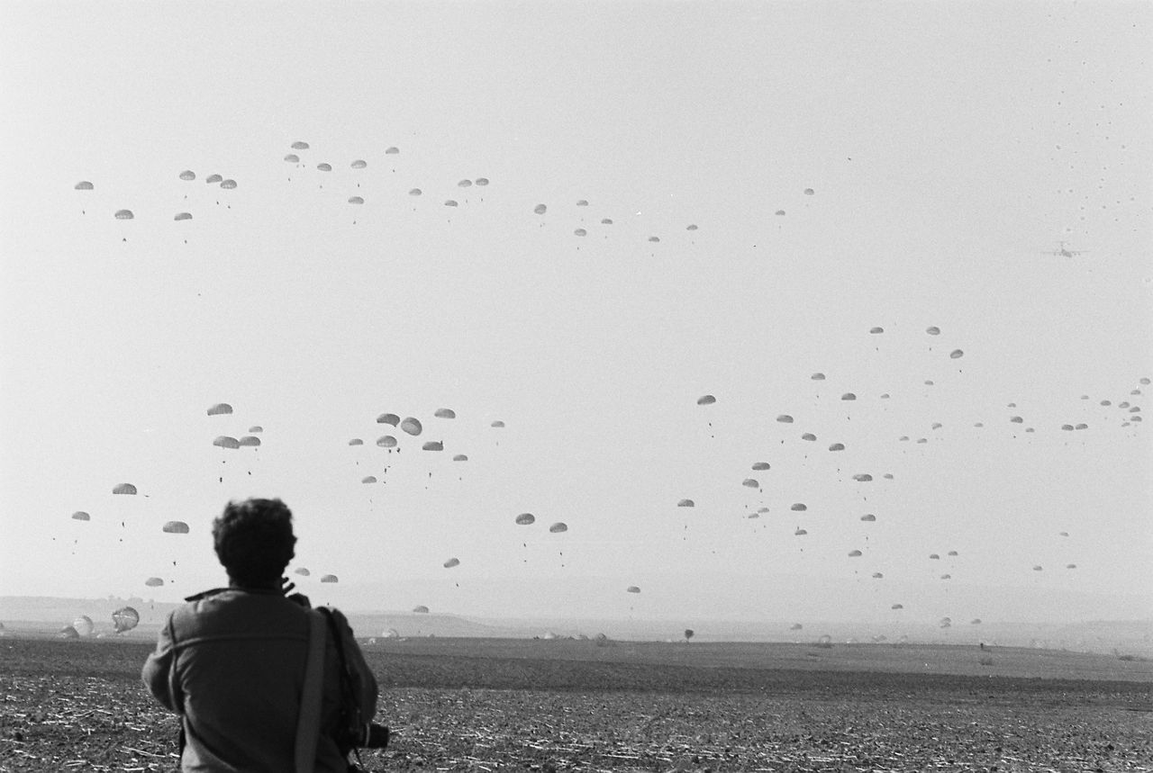 A photographer watches dozens of paratroopers drift down from the skies during exercise Display Determination in Türkiye.
