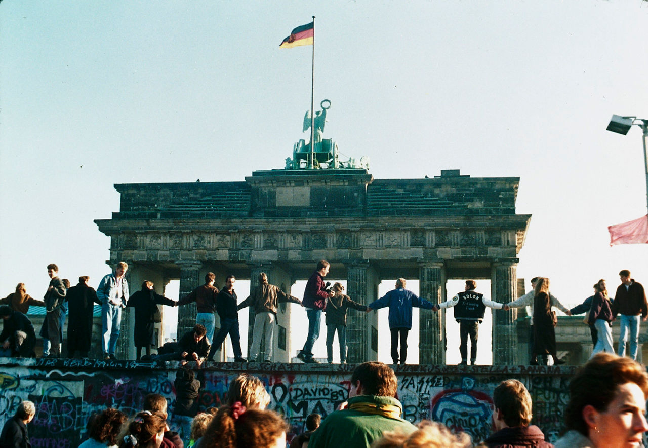 Berliners join hands atop the Berlin Wall near the Brandenburg Gate, celebrating the reunification of their city in November 1989.