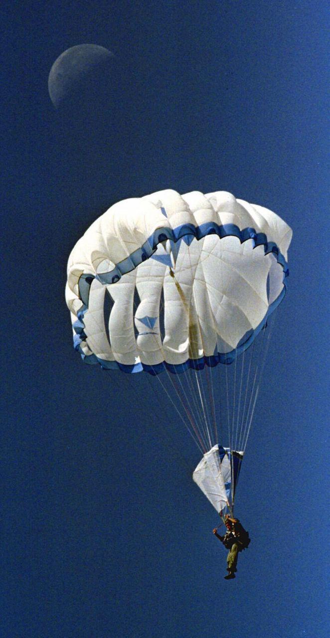 A paratrooper descends during the RAMBO 97 special forces competition in Bulgaria, with a view of the moon above. (Photo © Reuters/Alexei Dityakin)