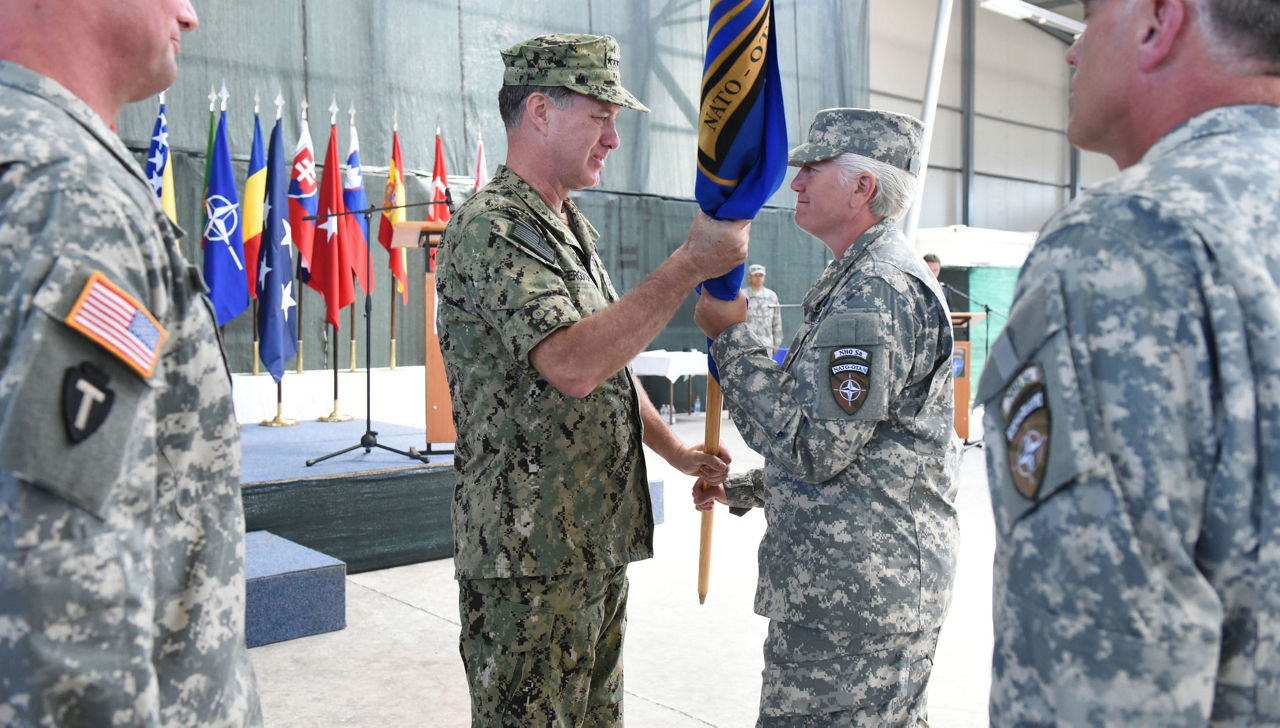 U.S. Navy Adm. Mark Ferguson, commander of Allied Joint Force Command Naples, U.S. Naval Forces Europe and Africa, passes the flag to U.S. Army Brig. Gen. Giselle Wilz, NATO Headquarters Sarajevo commander, during the transfer of authority ceremony at Camp Butmir in Sarajevo, Bosnia and Herzegovina June 9, 2015. Wilz is the first female commander of NATO Headquarters Sarajevo. (Courtesy Photo)