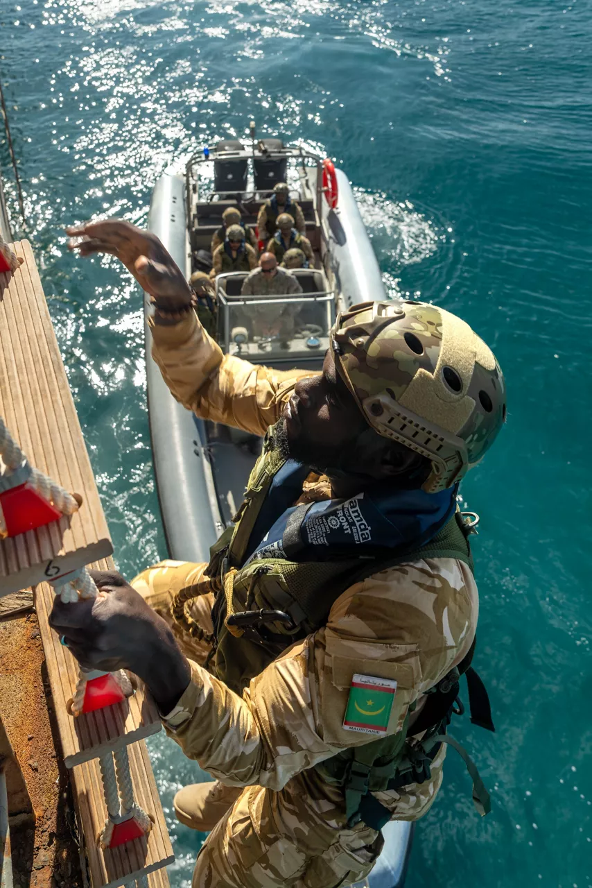 Mauritanian sailor ascends ladder during fast boat (RHIB) approach drills.

Sailors of the Mauritanian Navy conducted a three week-training programme on maritime security operations, hosted by the NATO Maritime Interdiction Operational Training Centre (NMIOTC), located near Chania, Greece, from 21 October to 8 November 2024. These training activities were carried out within the framework of NATO’s Defence and Related Security Capacity Building (DCB) Initiative.

