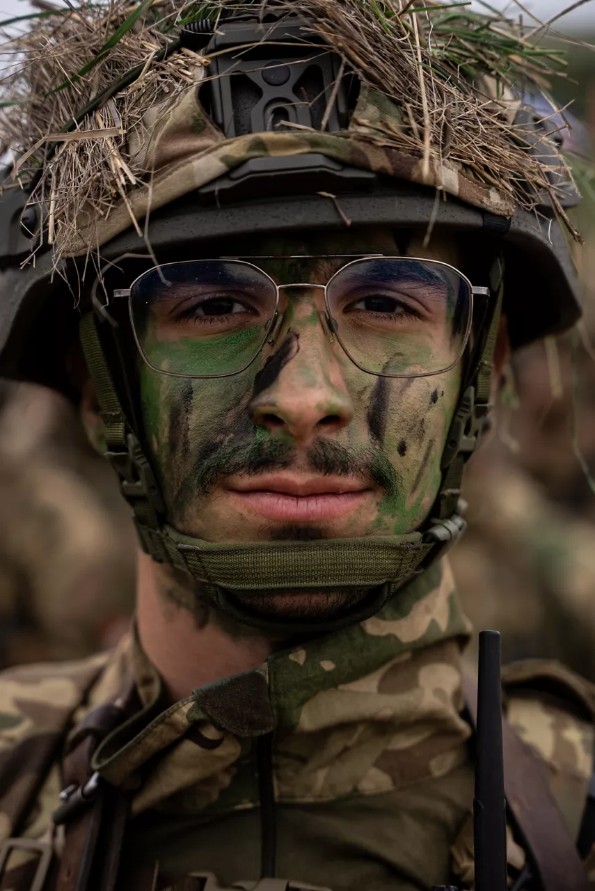 A Hungarian soldier sporting face paint and helmet scrim looks to the camera. Exercise Adaptive Hussars 2025 was the Hungarian Defence Forces’ largest and most complex military exercise since Hungary’s accession to NATO in 1999. It promoted cooperation between all NATO members contributing to the NATO’s multinational battlegroup in Hungary, and boosted Hungary’s  defence capabilities along with NATO defence plans and procedures.