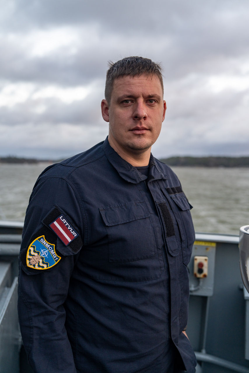 A Latvian sailor aboard SNMCMG1’s flagship LVNS Virsaitis stands for a portrait while the ship sails during exercise Freezing Winds.

NATO and its Allies are intensifying efforts to protect vital sea routes and critical infrastructure. Exercise Freezing Winds 2025 brought together ships from Standing NATO Mine Countermeasures Group One (SNMCMG1) and other Allied units to train side by side in the Baltic Sea’s harsh winter conditions. Over several days, naval forces, divers, and mine counter-measure teams practised joint operations to ensure readiness against diverse threats — from detecting and neutralising underwater threats to responding to disruptions affecting vital sea lines of communication. This exercise complements NATO’s Baltic Sentry enhanced vigilance activity, launched in January 2025 to strengthen surveillance and monitoring across the region. The exercise took place from 24 November to 4 December 2025.