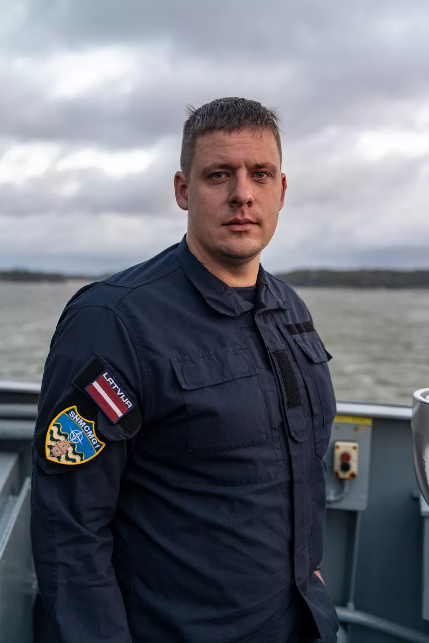 A Latvian sailor aboard SNMCMG1’s flagship LVNS Virsaitis stands for a portrait while the ship sails during exercise Freezing Winds.

NATO and its Allies are intensifying efforts to protect vital sea routes and critical infrastructure. Exercise Freezing Winds 2025 brought together ships from Standing NATO Mine Countermeasures Group One (SNMCMG1) and other Allied units to train side by side in the Baltic Sea’s harsh winter conditions. Over several days, naval forces, divers, and mine counter-measure teams practised joint operations to ensure readiness against diverse threats — from detecting and neutralising underwater threats to responding to disruptions affecting vital sea lines of communication. This exercise complements NATO’s Baltic Sentry enhanced vigilance activity, launched in January 2025 to strengthen surveillance and monitoring across the region. The exercise took place from 24 November to 4 December 2025.