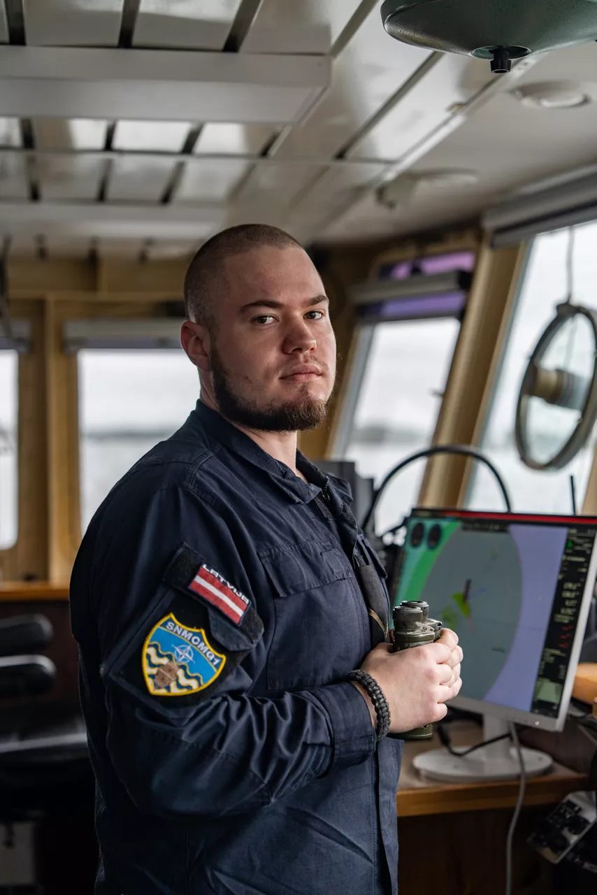 A Latvian sailor aboard SNMCMG1’s flagship LVNS Virsaitis poses for a photo while sailing during exercise Freezing Winds.

NATO and its Allies are intensifying efforts to protect vital sea routes and critical infrastructure. Exercise Freezing Winds 2025 brought together ships from Standing NATO Mine Countermeasures Group One (SNMCMG1) and other Allied units to train side by side in the Baltic Sea’s harsh winter conditions. Over several days, naval forces, divers, and mine counter-measure teams practised joint operations to ensure readiness against diverse threats — from detecting and neutralising underwater threats to responding to disruptions affecting vital sea lines of communication. This exercise complements NATO’s Baltic Sentry enhanced vigilance activity, launched in January 2025 to strengthen surveillance and monitoring across the region. The exercise took place from 24 November to 4 December 2025.