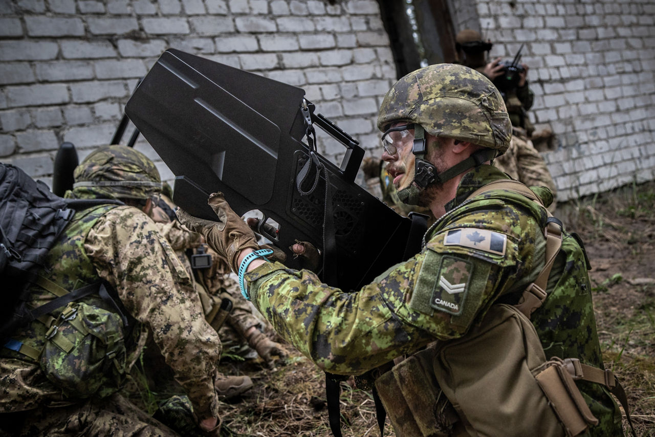 A Canadian Armed Forces counter drone specialist observing drone while holding a signal jamming device. NATO’s Multinational Brigade in Latvia regularly runs training exercises where troops integrate all kinds of drones, making sure Allied forces keep up with innovations in modern warfare.